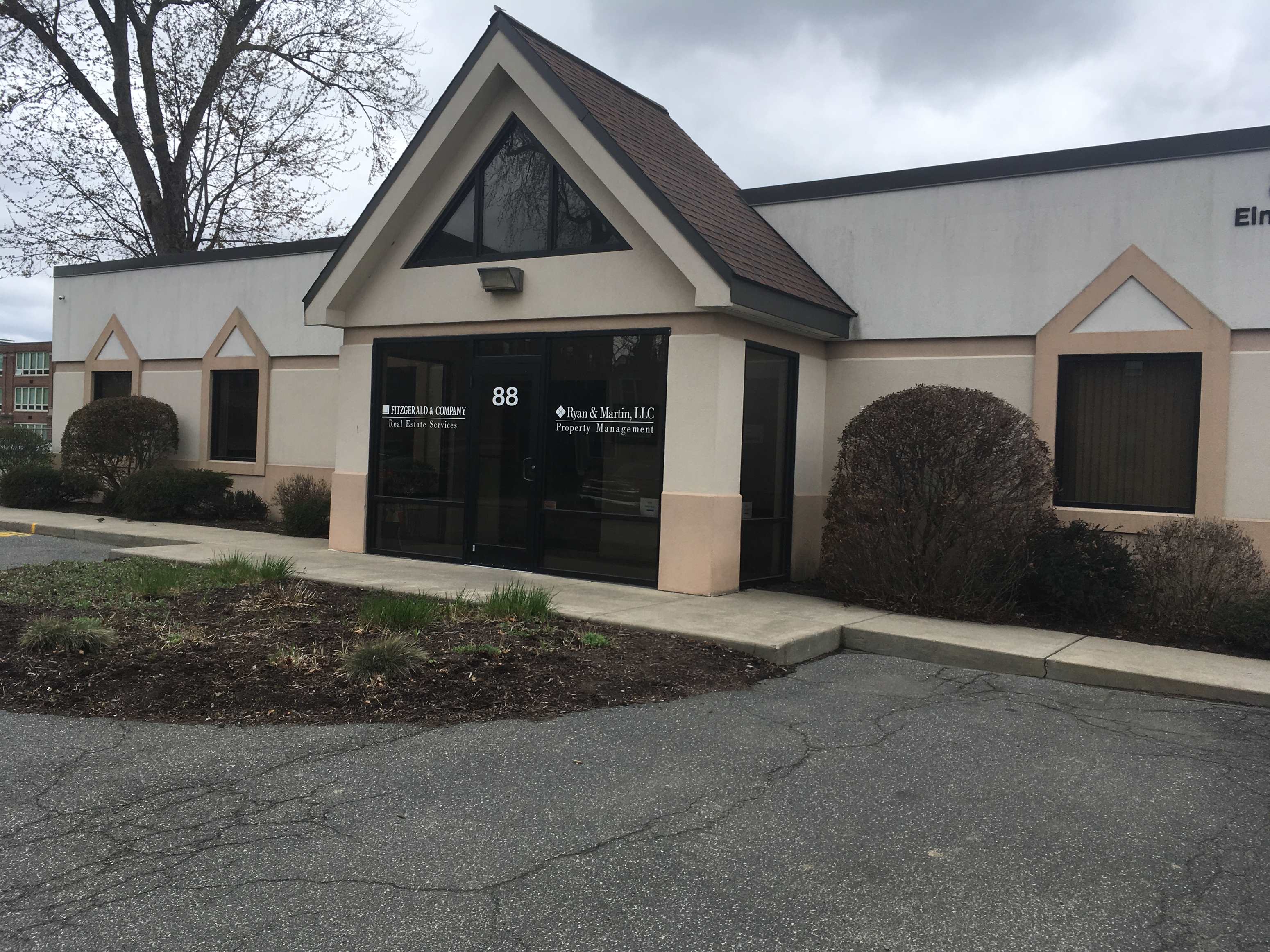 the front of a building with a black door and a sidewalk