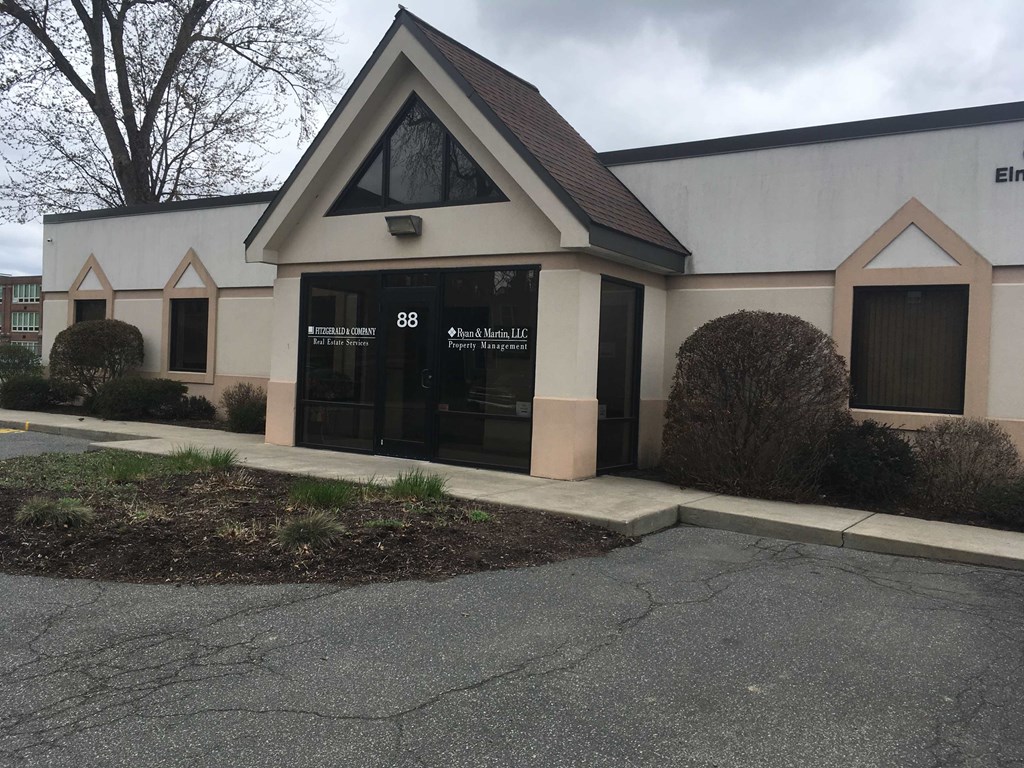 the front of a building with a black door and a sidewalk