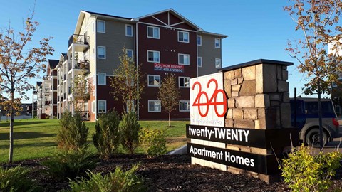 A sign for Twenty Twenty Apartment Homes in front of a building.
