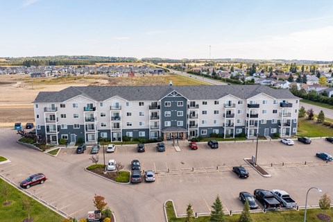 A large white building with a parking lot in front.