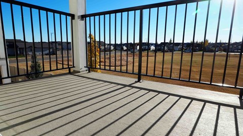 A balcony with a black railing and wooden floor.