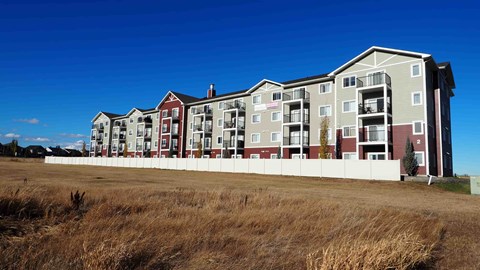 A row of apartment buildings with a field in the foreground.