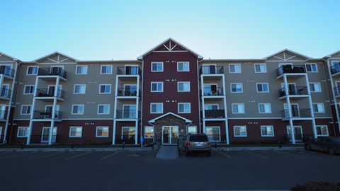 A large apartment complex with a parking lot in front.
