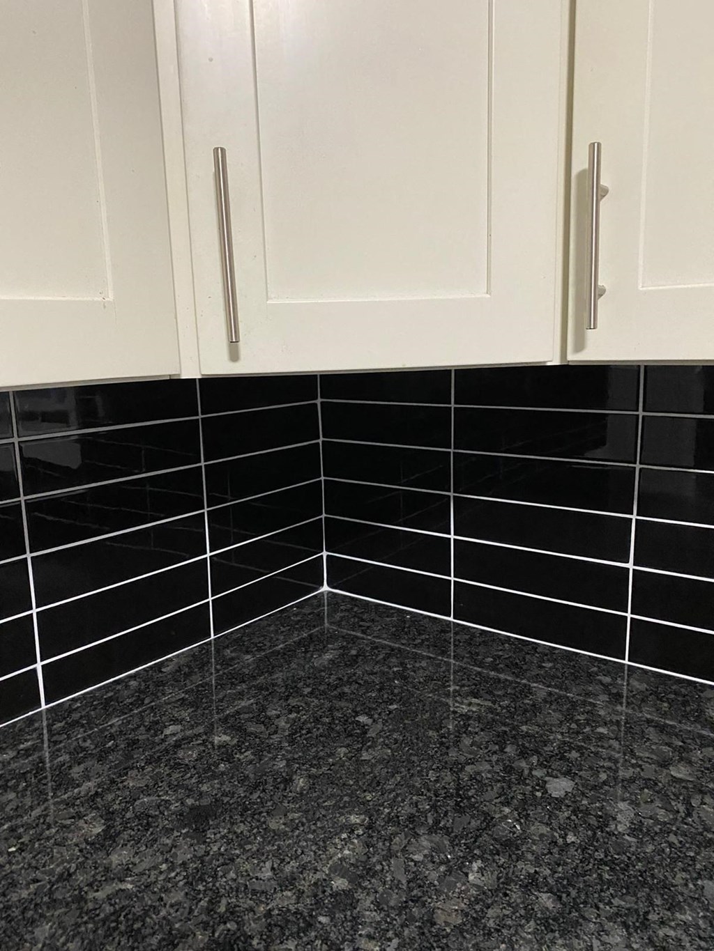 a bathroom with black tiles and white cabinets