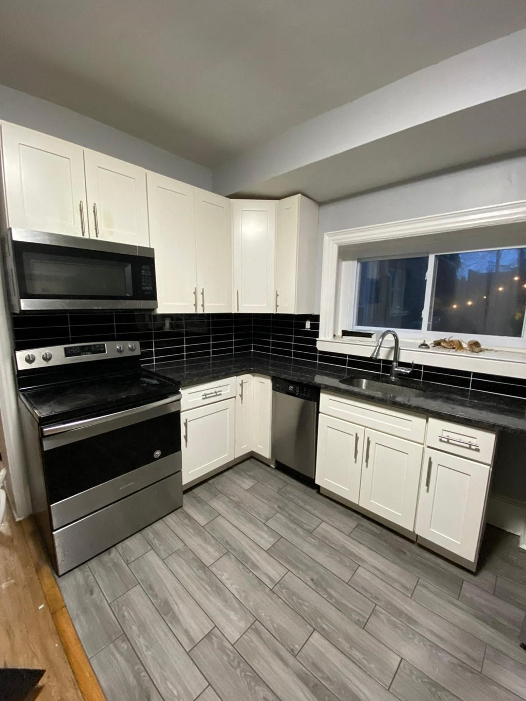a kitchen with white cabinets and a stove and a window