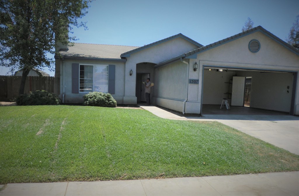 a house with a yard and a person standing in the door