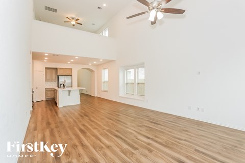 A spacious room with wooden floors and a ceiling fan.