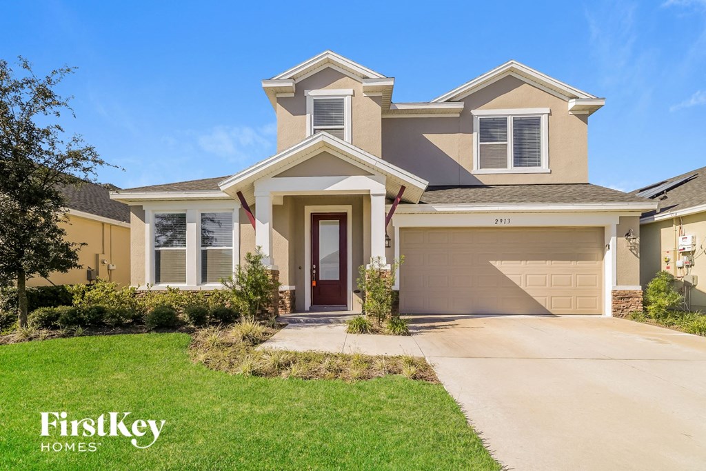 a beige house with a garage door and a lawn