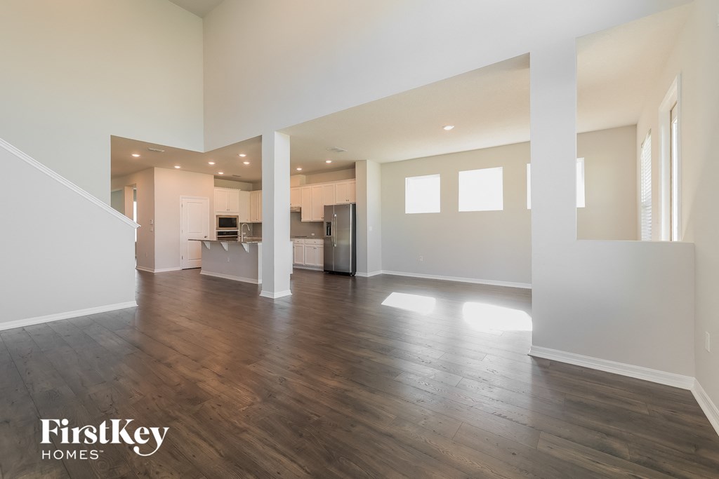an empty living room and kitchen with wood floors and white walls