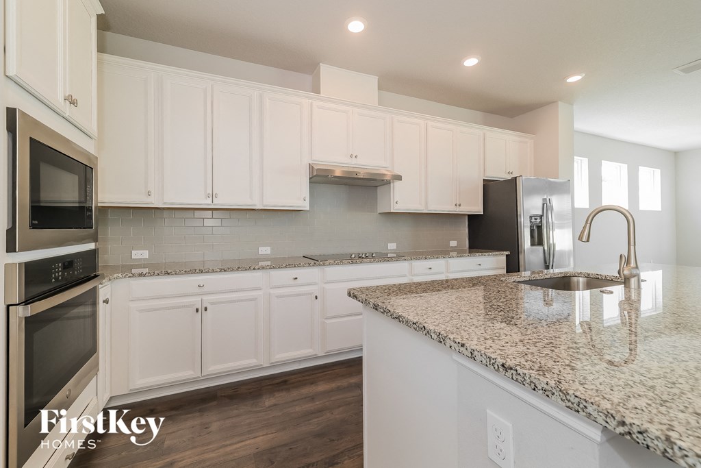 a white kitchen with granite counter tops and white cabinets