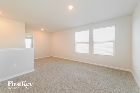 a spacious living room with white carpet and two windows
