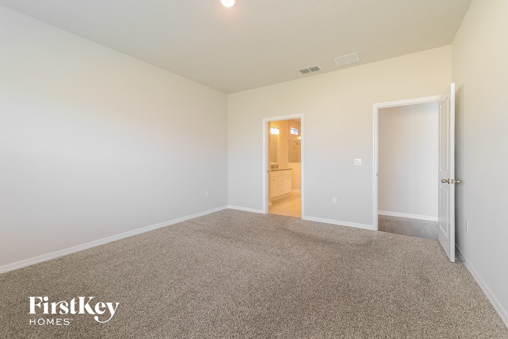 a bedroom with a carpeted floor and a door to a bathroom