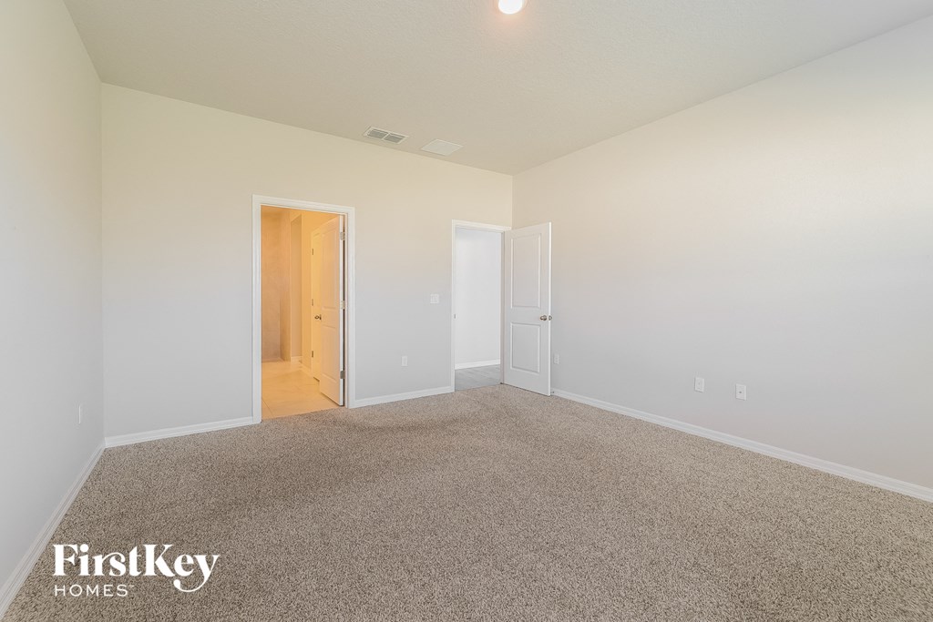 a spacious living room with carpet and white walls