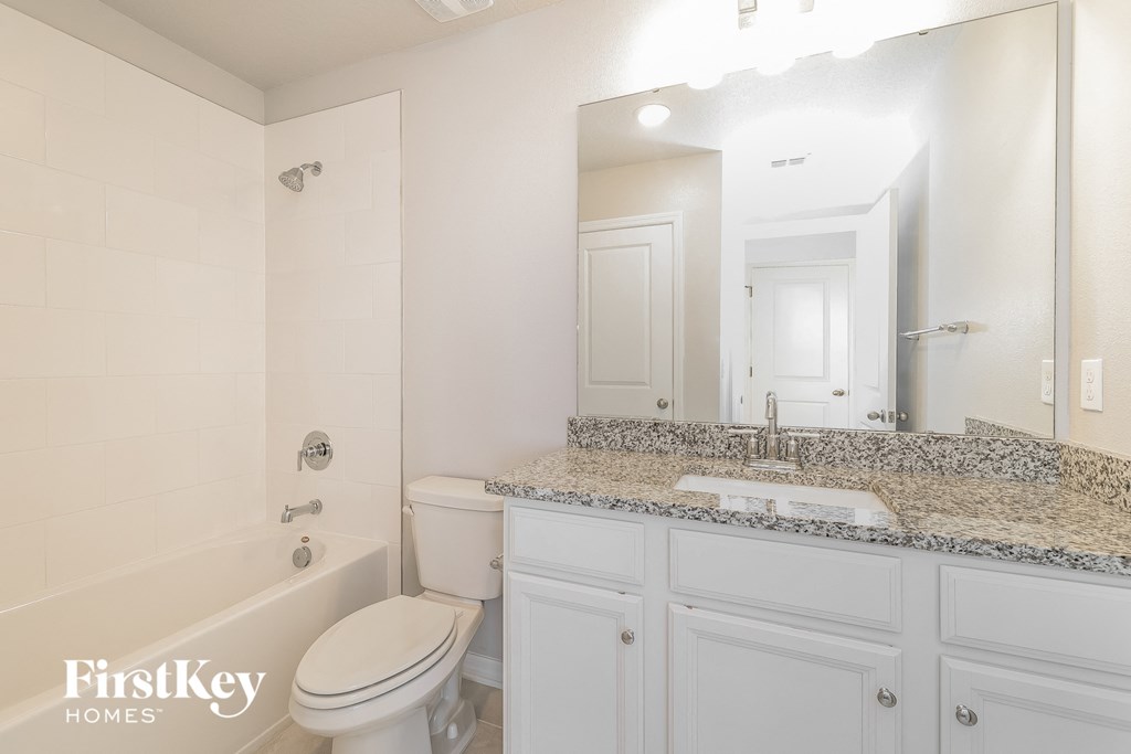 a bathroom with white cabinets and a white toilet and tub and a sink