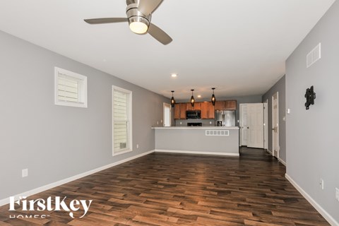 A spacious room with wooden floors and a ceiling fan.