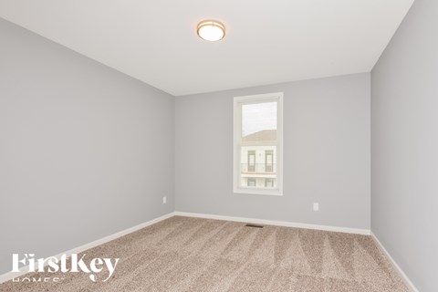 A room with a carpeted floor and a window showing a building outside.