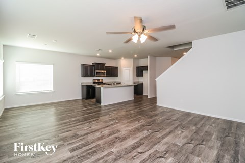 A spacious room with wooden flooring and a ceiling fan.