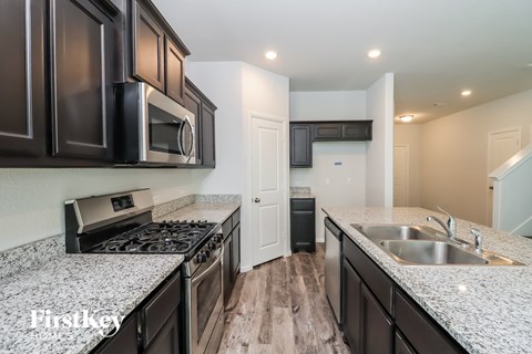 A kitchen with dark brown cabinets and a granite countertop.