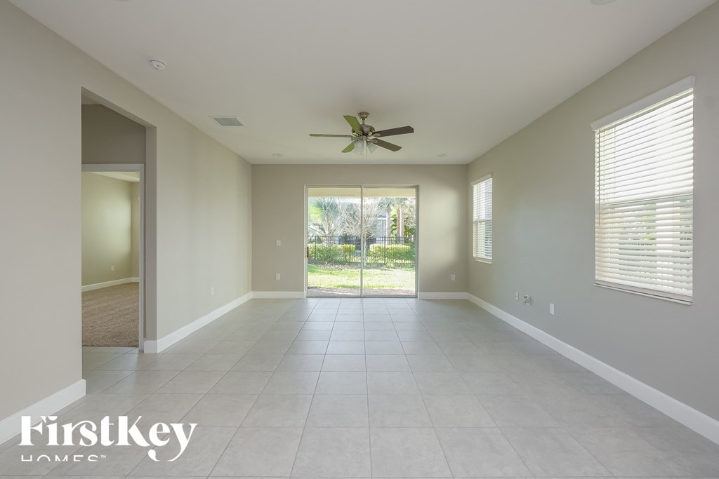 an empty living room with a ceiling fan and a door to the backyard