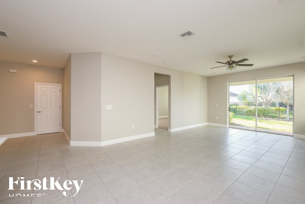an empty living room with a ceiling fan and a glass door