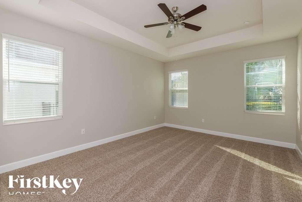 an empty living room with a ceiling fan and two windows