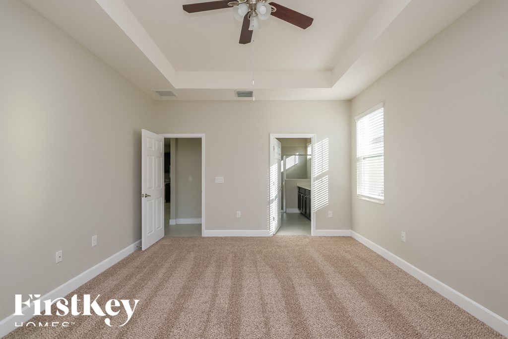 a spacious living room with carpet and a ceiling fan