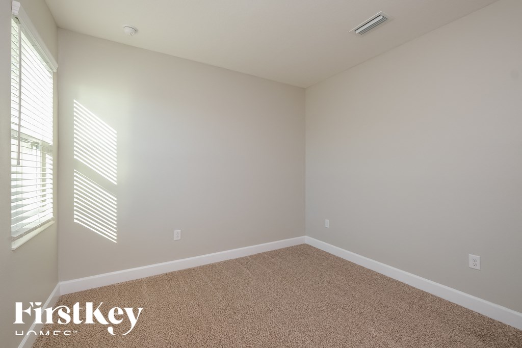a empty room with beige carpet and a large window