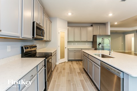 A kitchen with white cabinets and a tile floor.