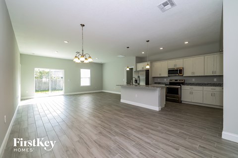A spacious kitchen and living room with wooden flooring and white walls.