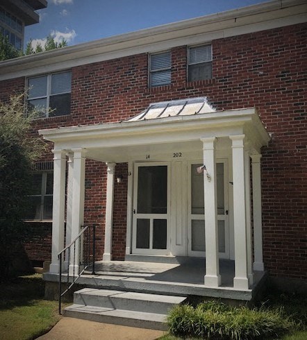 A red brick house with a white door and windows.