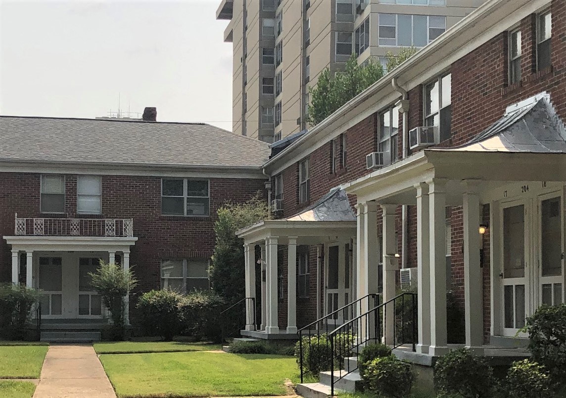 A red brick house with a white porch and a black metal railing.
