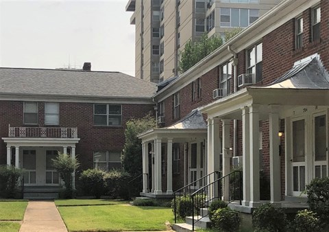 A red brick house with a white porch and a black metal railing.
