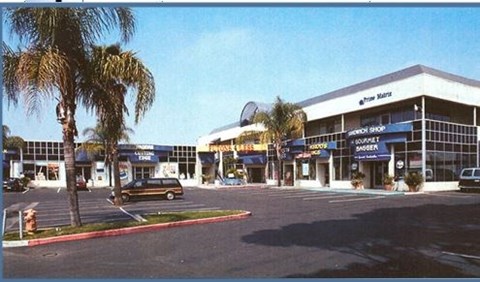 a parking lot with a building and palm trees