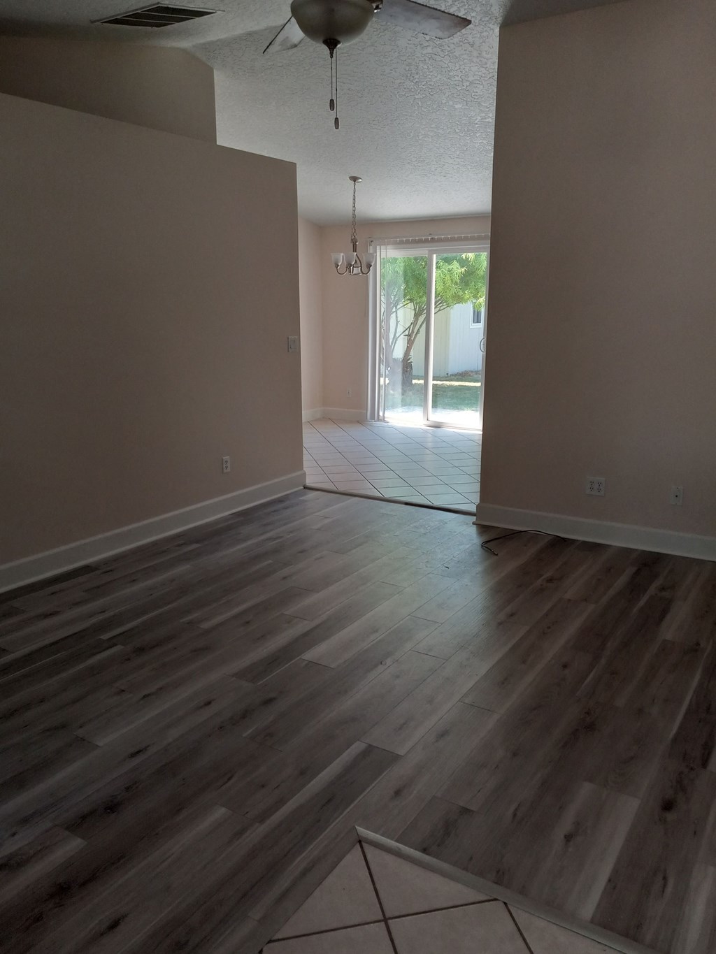 an empty living room with wooden floors and a sliding glass door