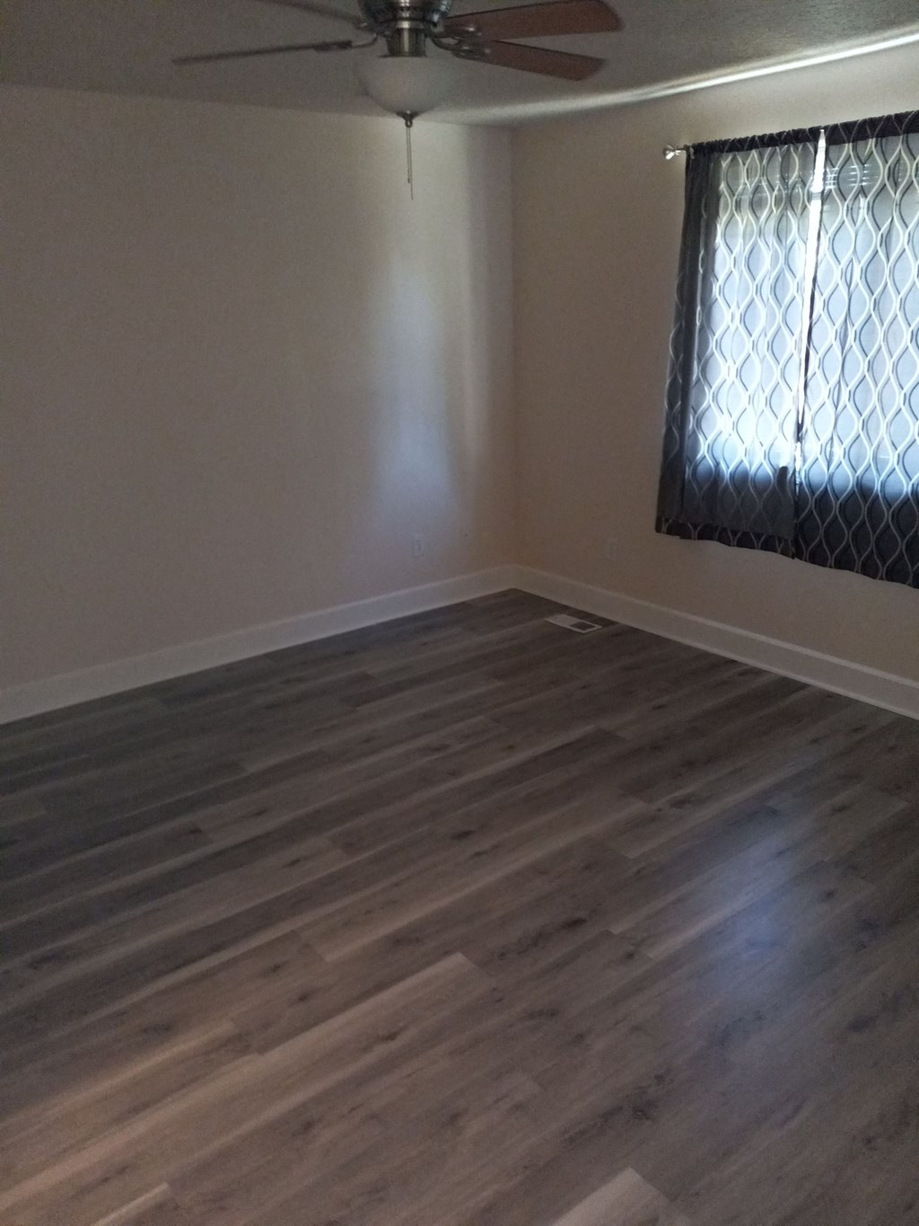 an empty living room with wood floors and a window