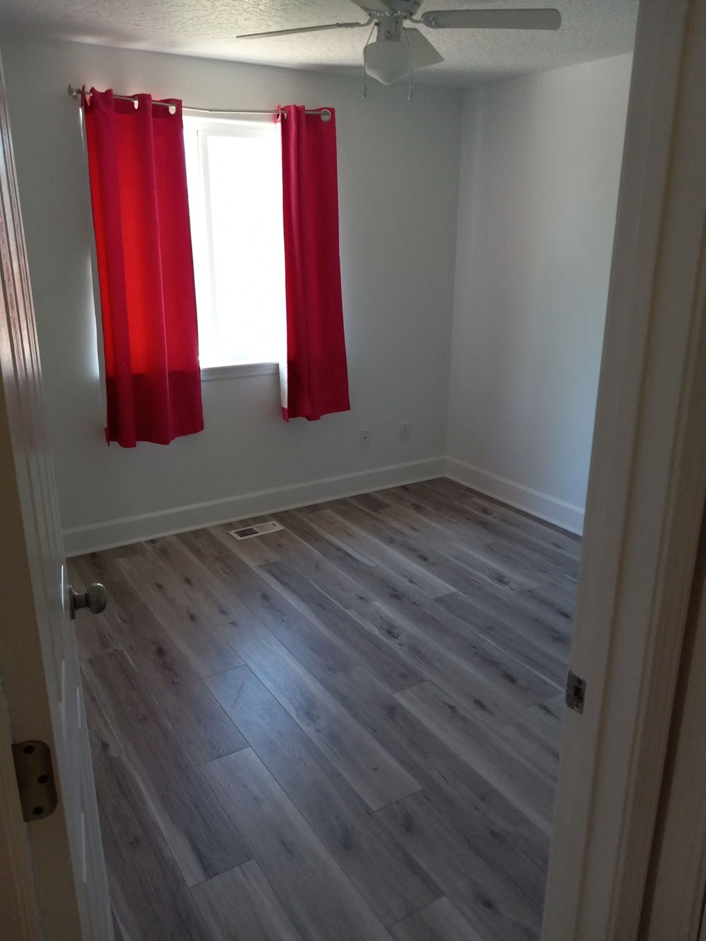 a room with wooden floors and a red curtain