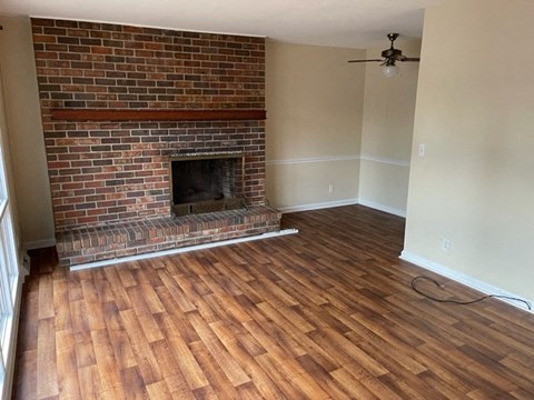 a living room with a brick fireplace and a wooden floor