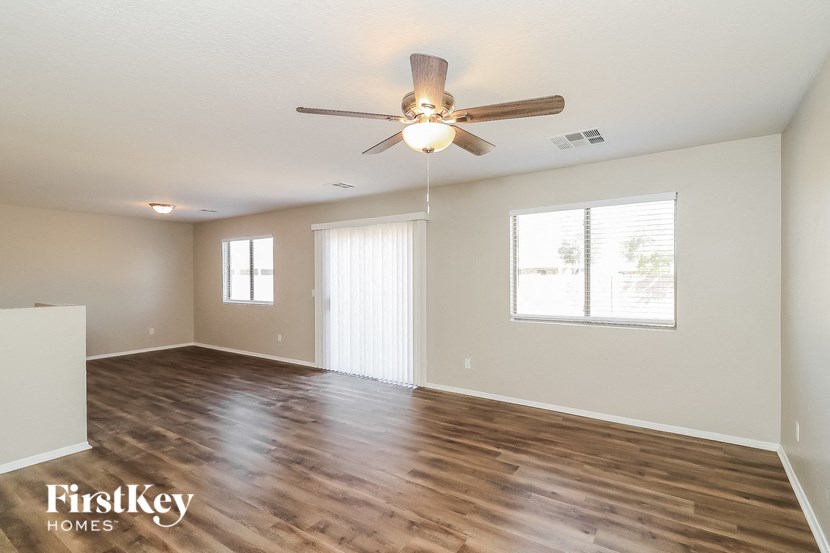 an empty living room with a ceiling fan and a window