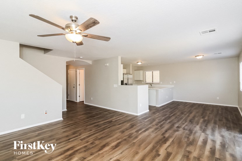 an empty living room and kitchen with a ceiling fan