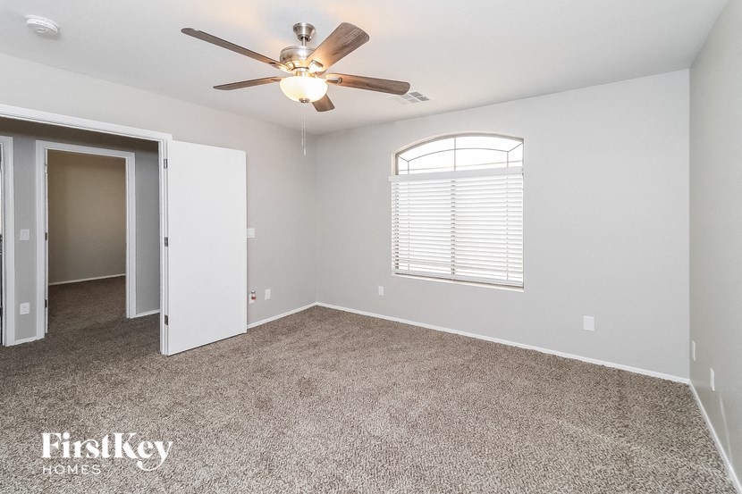 an empty living room with a ceiling fan and a window