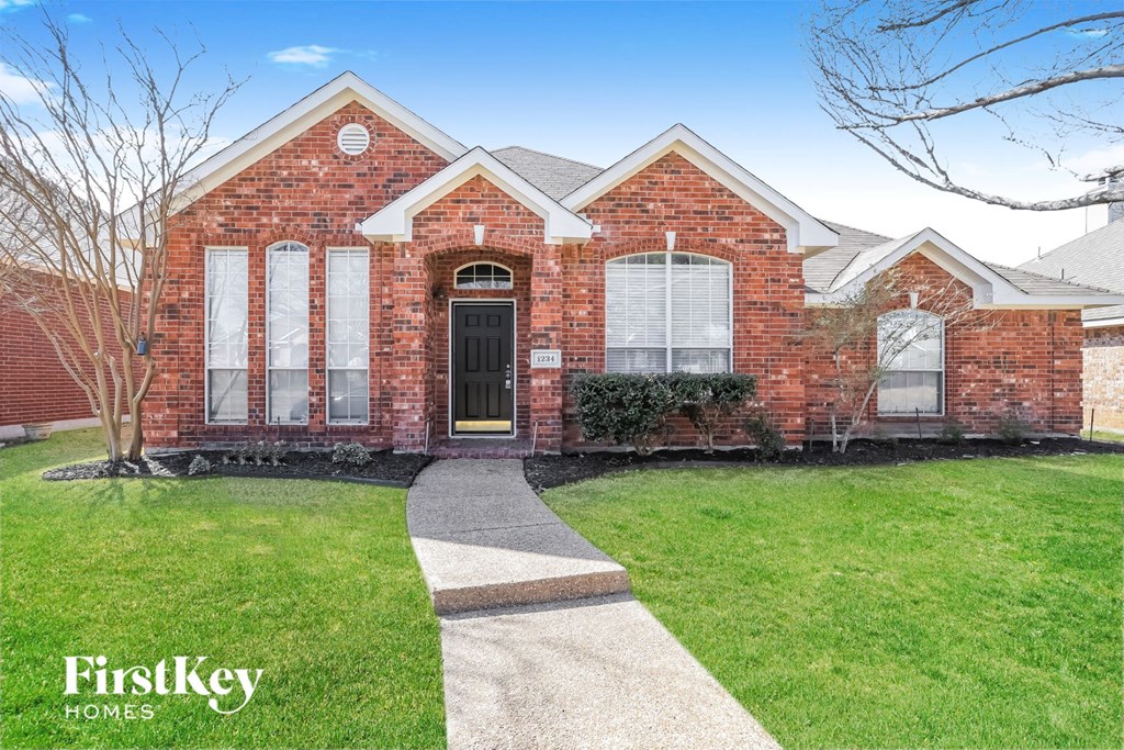the front of a brick house with a sidewalk in front of it