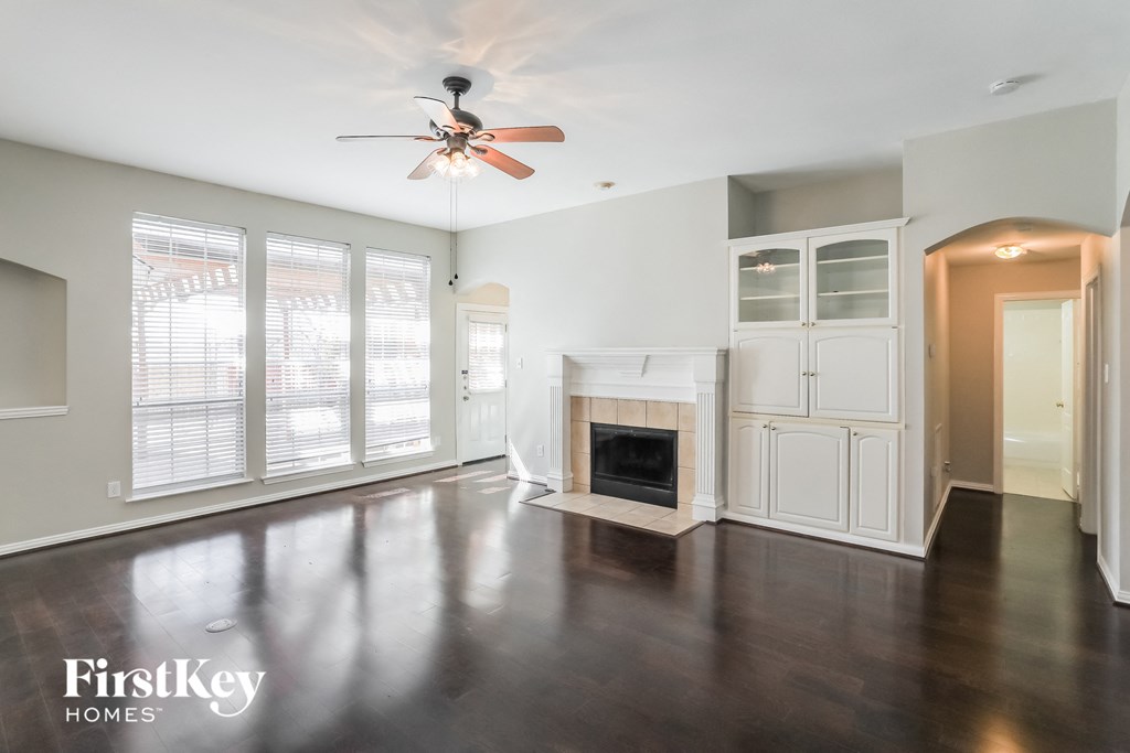 an empty living room with a fireplace and a ceiling fan