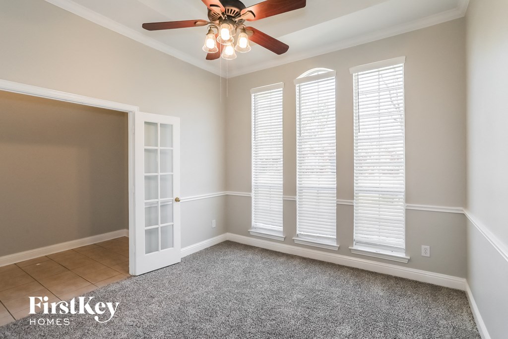 a living room with a ceiling fan and three windows