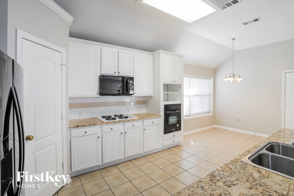 a kitchen with white cabinets and granite counter tops and a sink