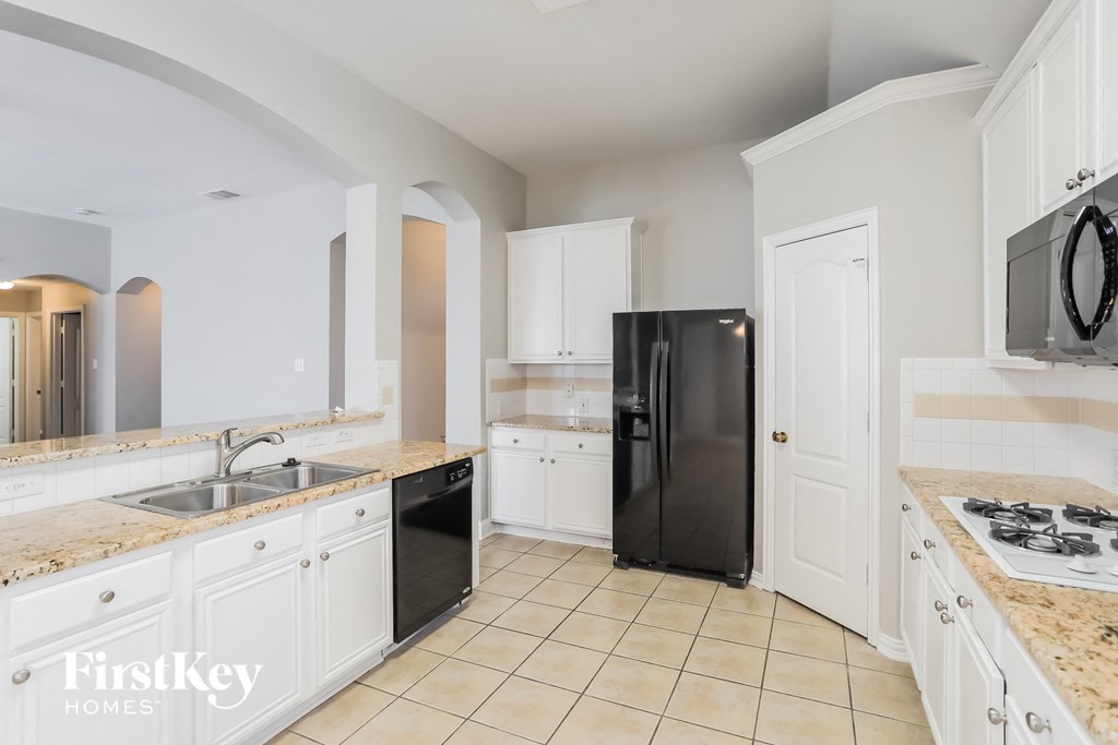 a large kitchen with white cabinets and black appliances