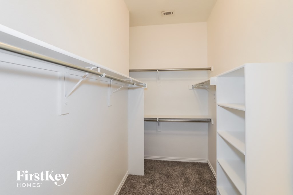 a walk in closet with shelves and a mirrored closet door