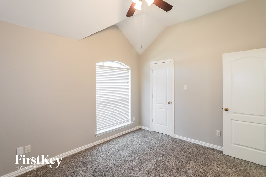 a bedroom with white doors and a carpeted floor and a ceiling fan