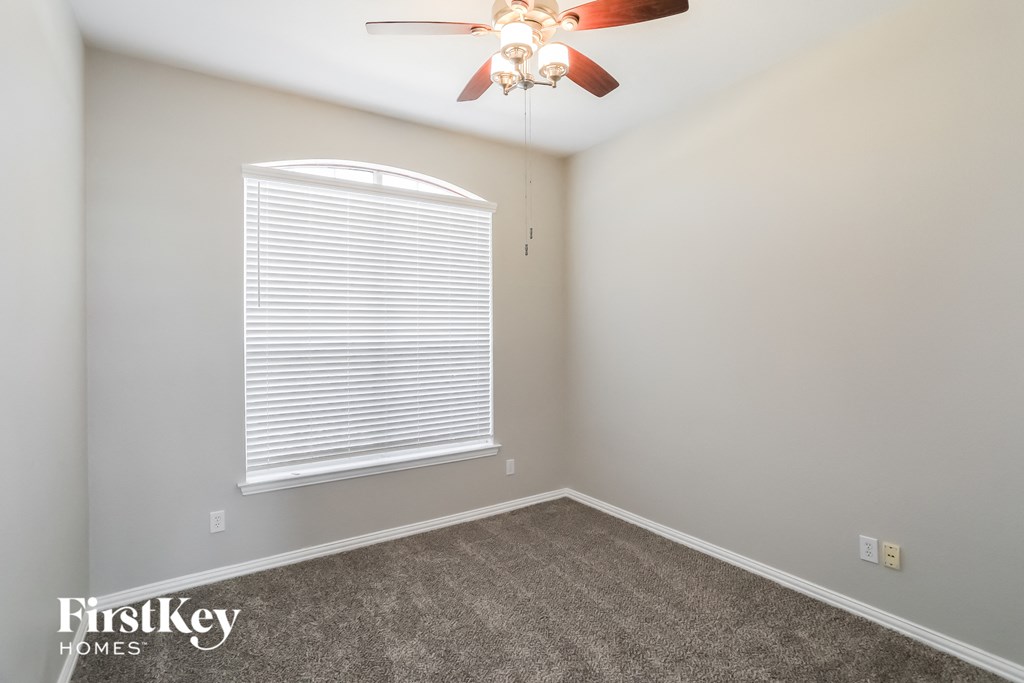 an empty room with a ceiling fan and a window