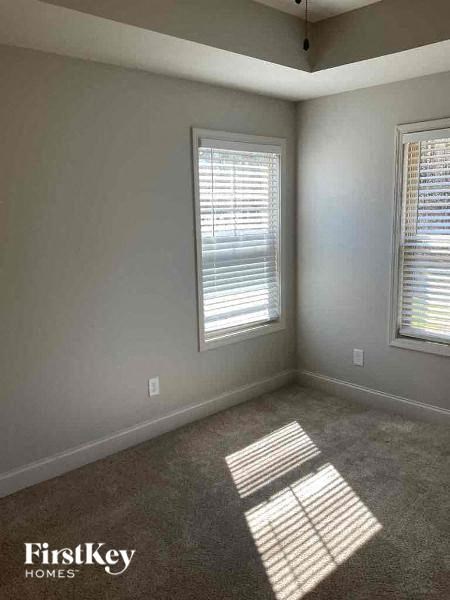 an empty room with two windows and a carpet