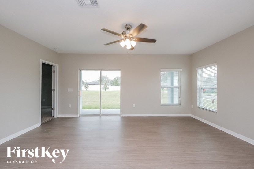 A spacious room with a ceiling fan and sliding glass doors leading to a grassy area.